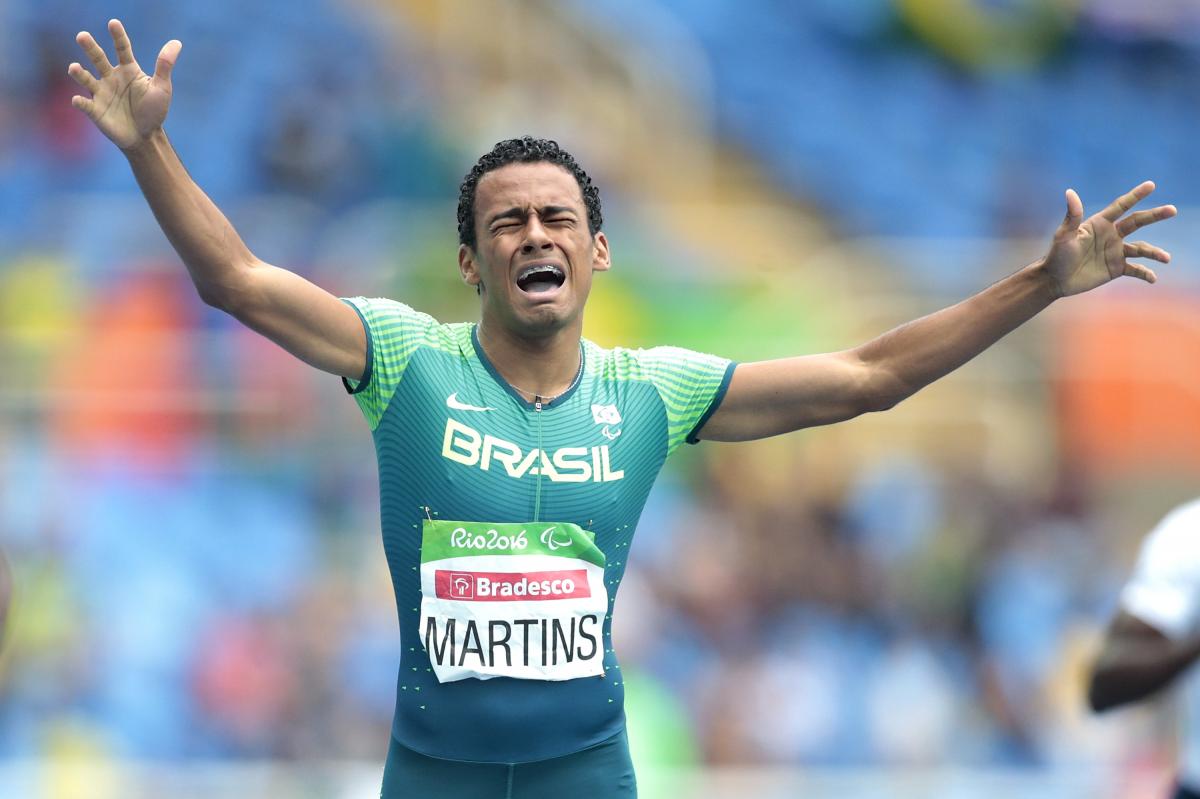 a Para athlete cries out in celebration as he crosses the finish line