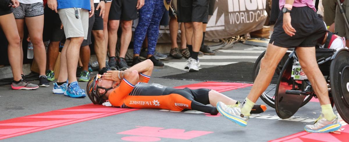 a man lies on the road celebrating after crossing the finish line