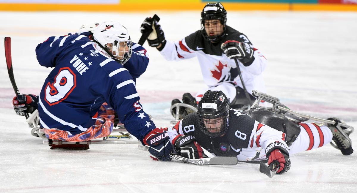 Para ice hockey players contest a puck