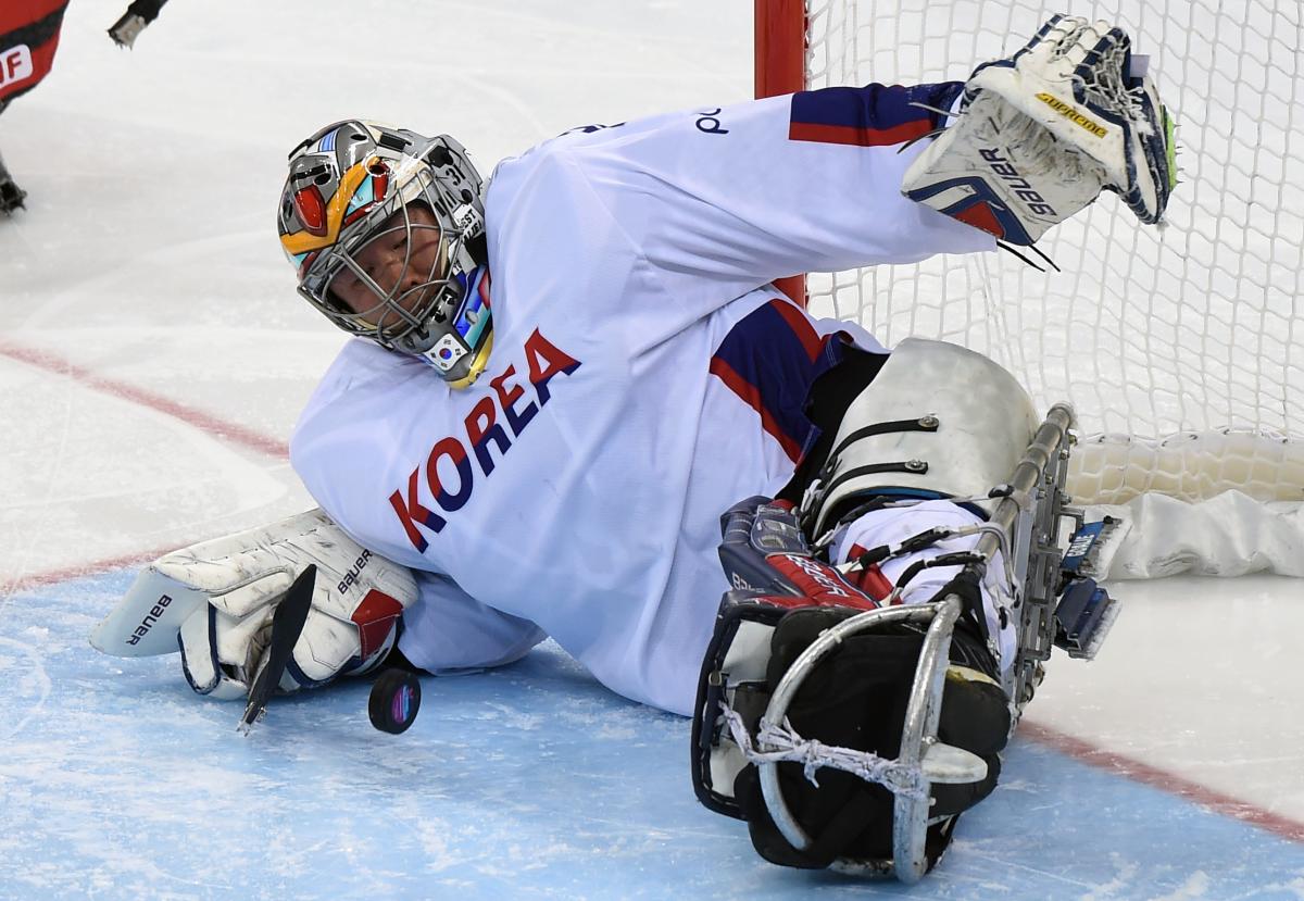 a male Para ice hockey player makes a save