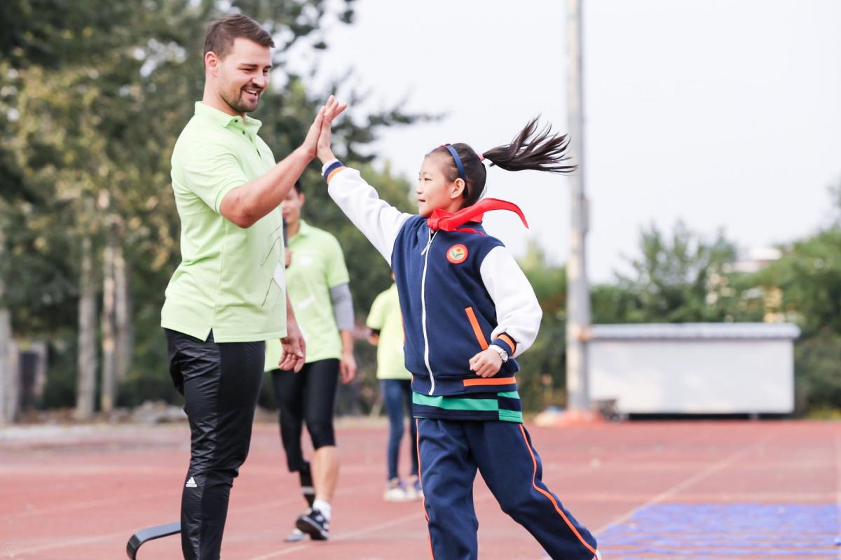 Heinrich Popow in China a male Para athlete high fives a girl on the track
