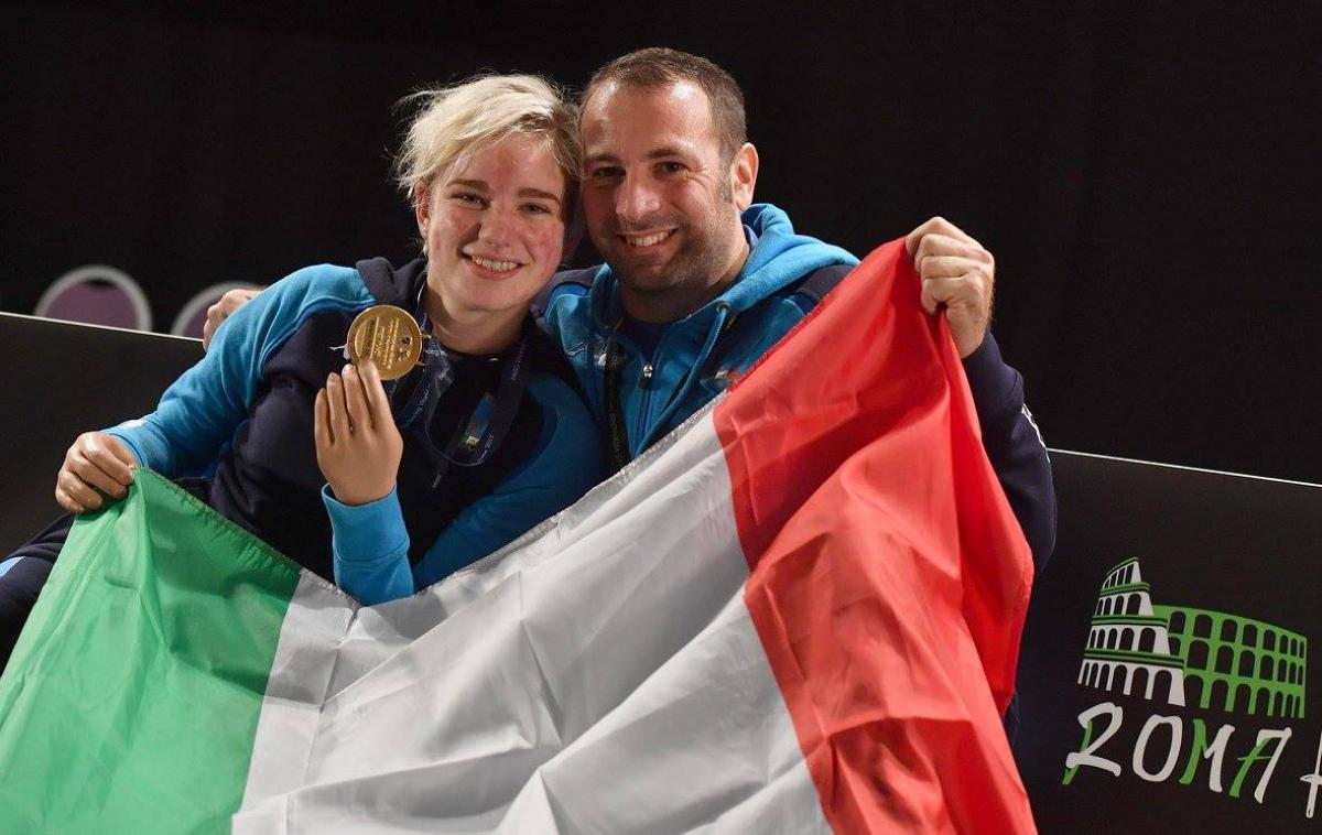 a man a woman smiling with a gold medal and the Italian flag