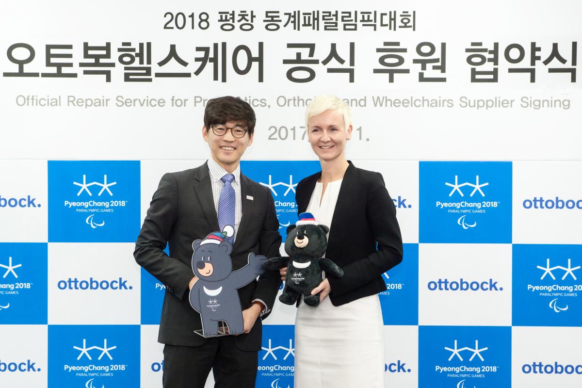 a man and a woman standing holding mascots