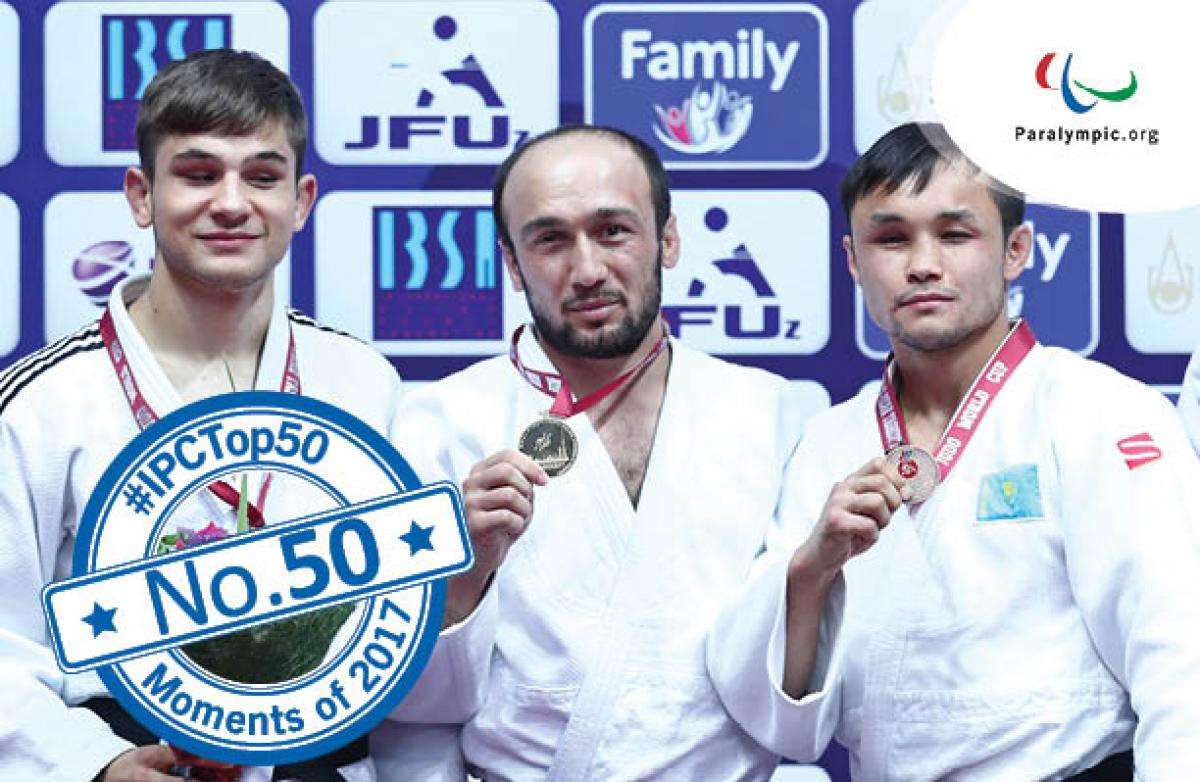 a group of four judokas stand smiling on the podium