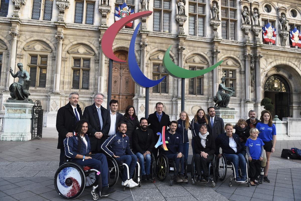 IPC President Andrew Parsons in Paris Group of people smiling in front of the Agitos logo and the municipality of Paris