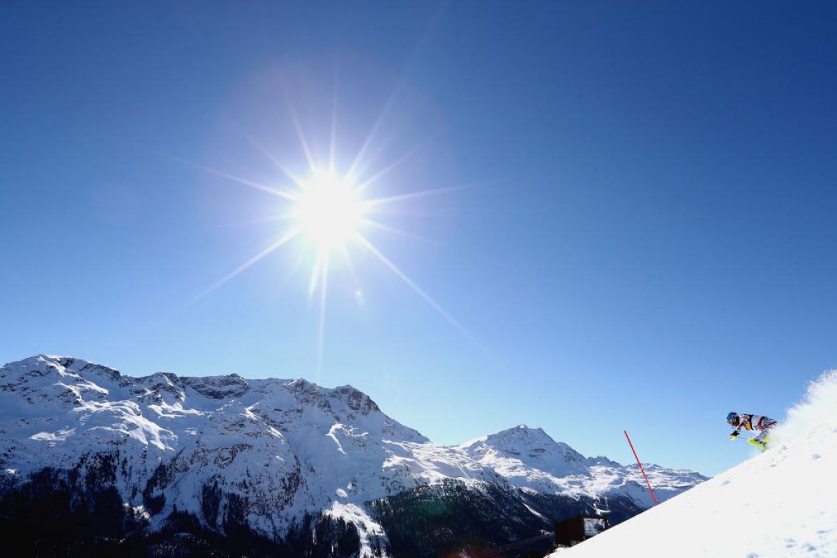 a skier comes down a slope in bright sunshine