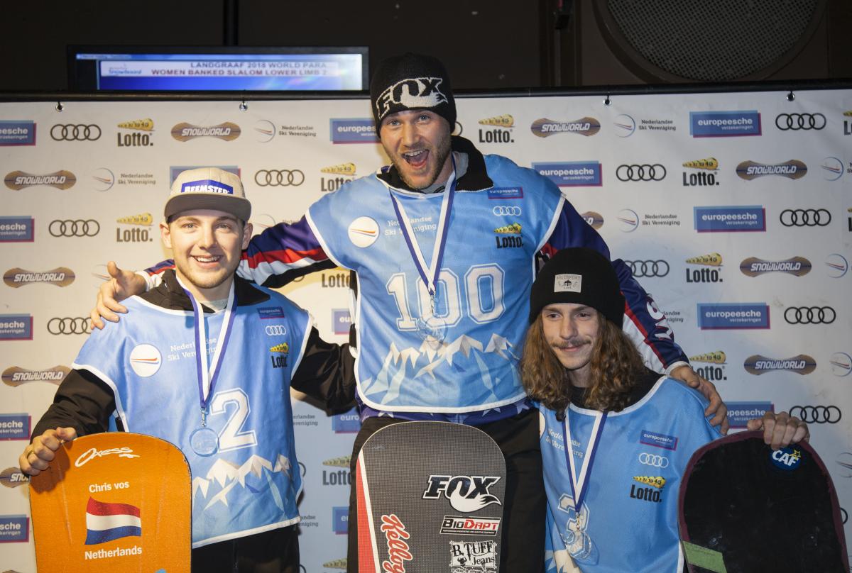 Three male snowboarders pose on podium