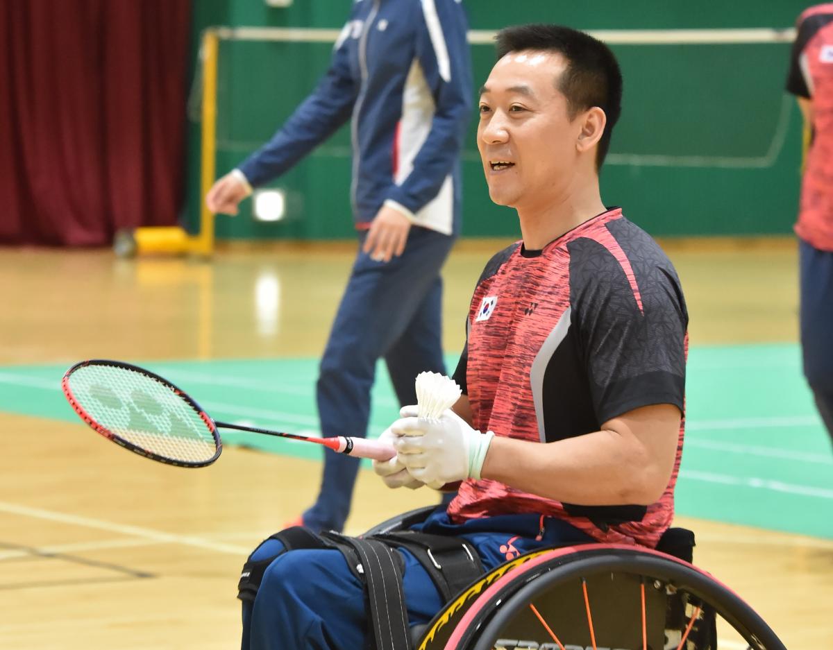 Kyung Hoon Kim A male Para badminton player holds a shuttlecock and racquet