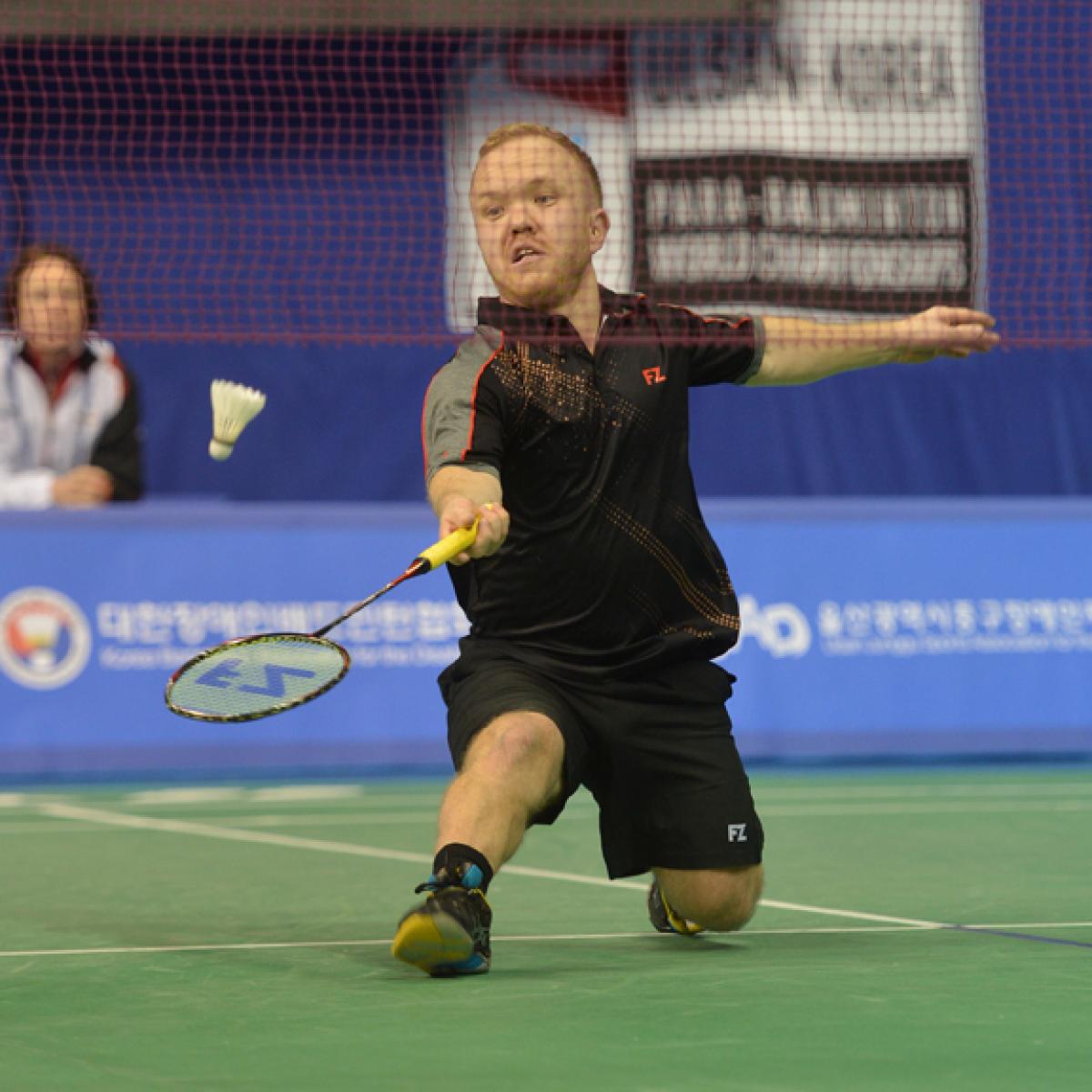 a male Para badminton player goes for a shot