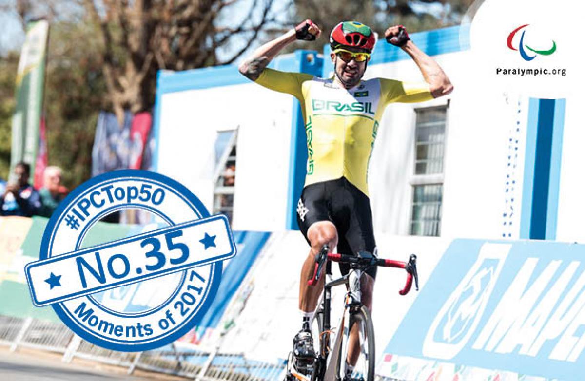 a male Para cyclist raises his arms in celebration as he crosses the finish line