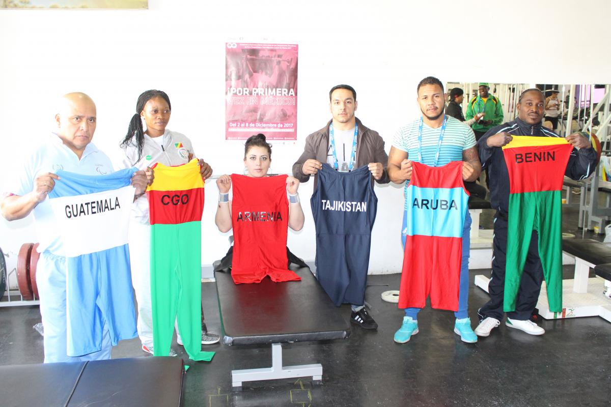 a group of Para powerlifters hold up their lifting suits