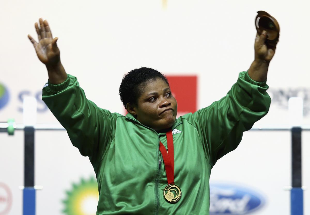 a female powerlifter raises her arms in celebration