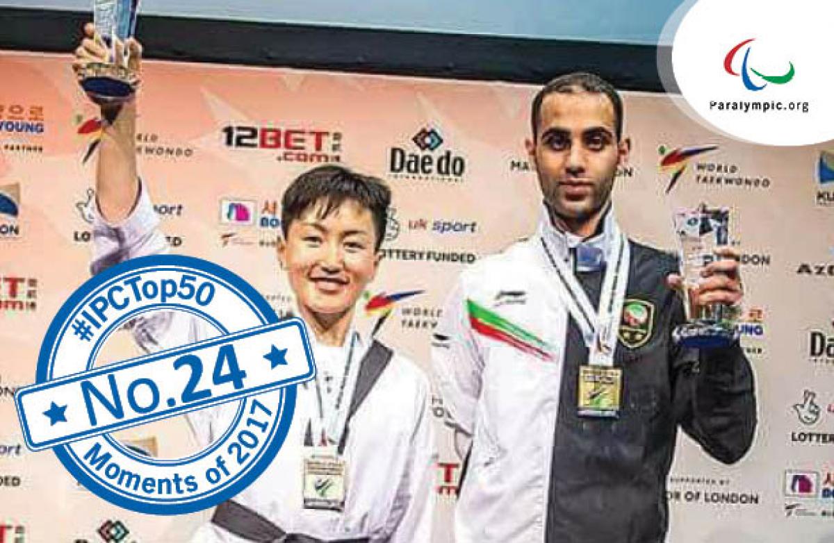 a female Para taekwondo fighter raises her trophy and smiles