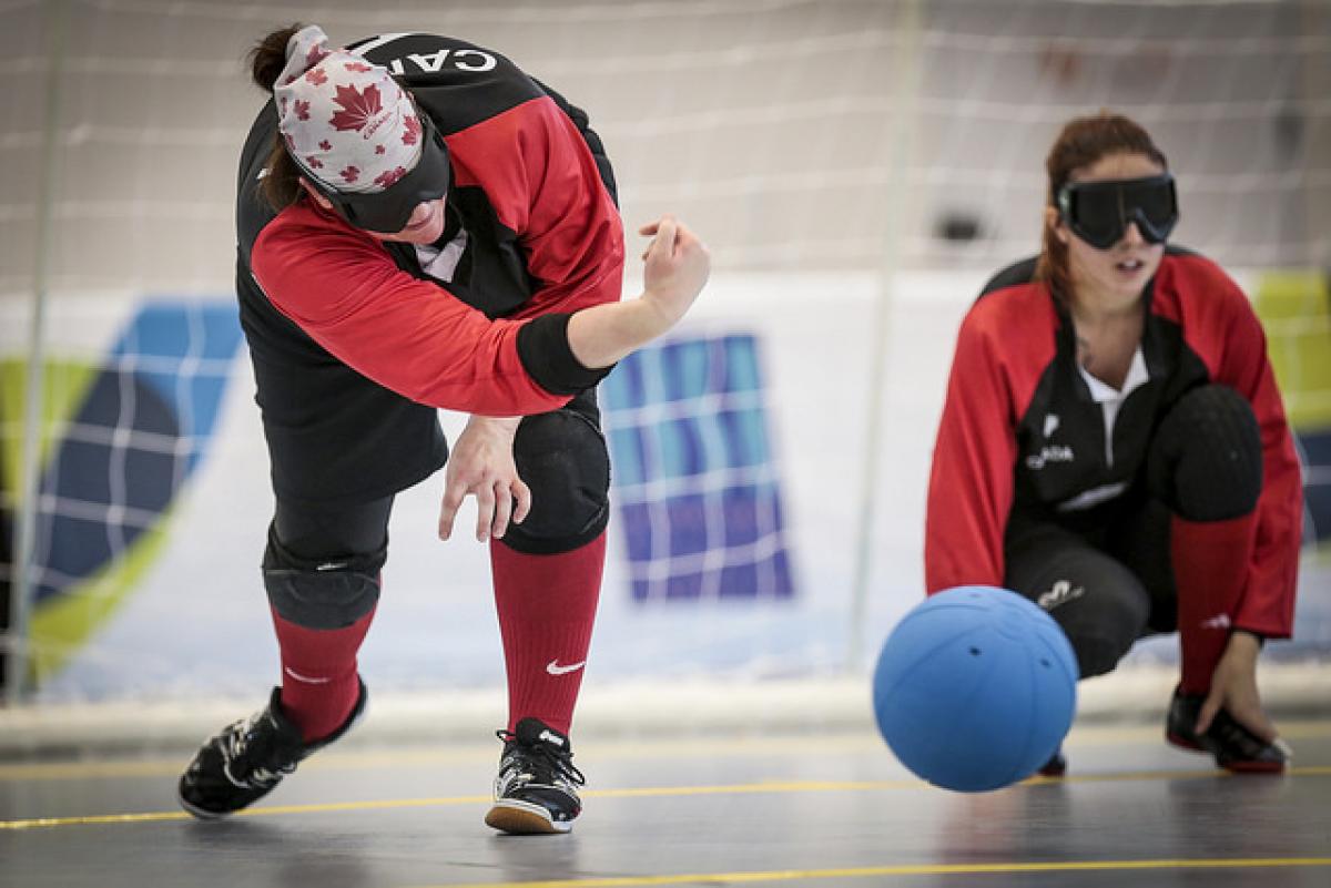 Woman goalball player rolls a ball