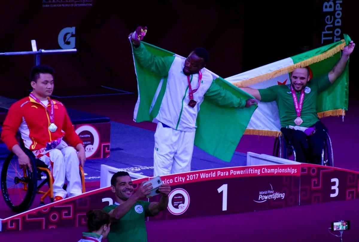 Paul Kehinde - Mexico City 2017 three powerlifters on the podium, two holding up flags