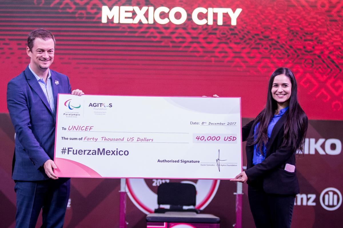 IPC President Andrew Parsons presents the cheque to UNICEF representative Jimena Lazcano