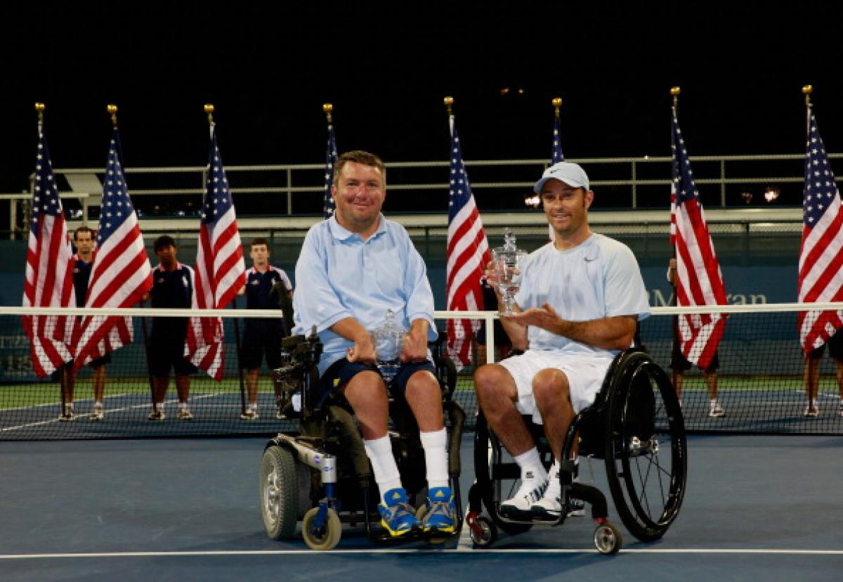 Two men in wheelchairs pose for photo on tennis court