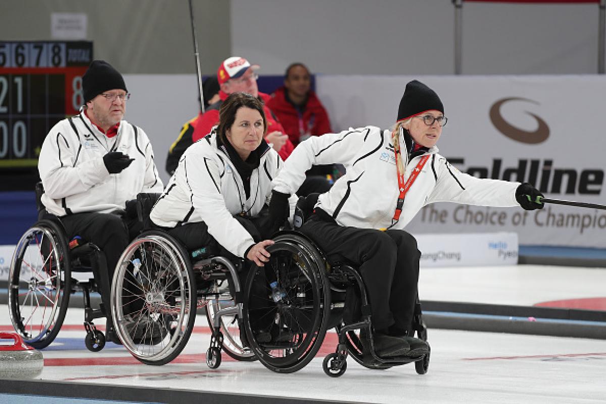 a female wheelchair curler pushes the stone across the ice