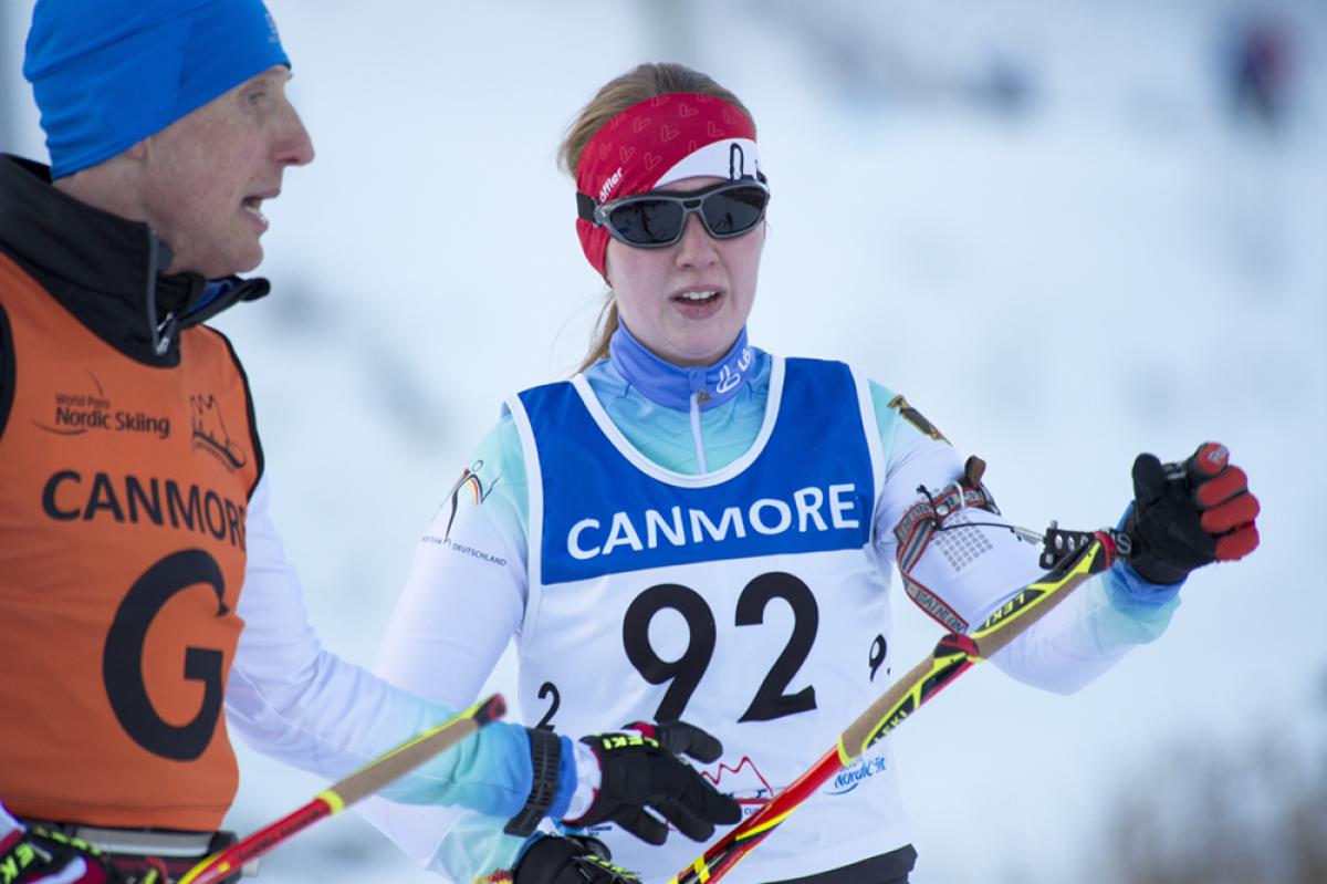 Two people talking, one on the right is competing in Para Nordic Skiing