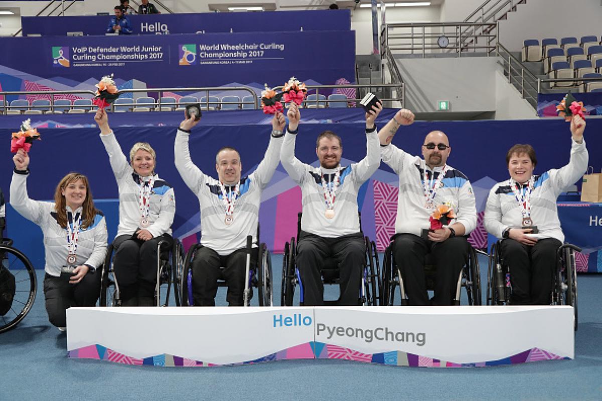a group of wheelchair curlers celebrate with their medals