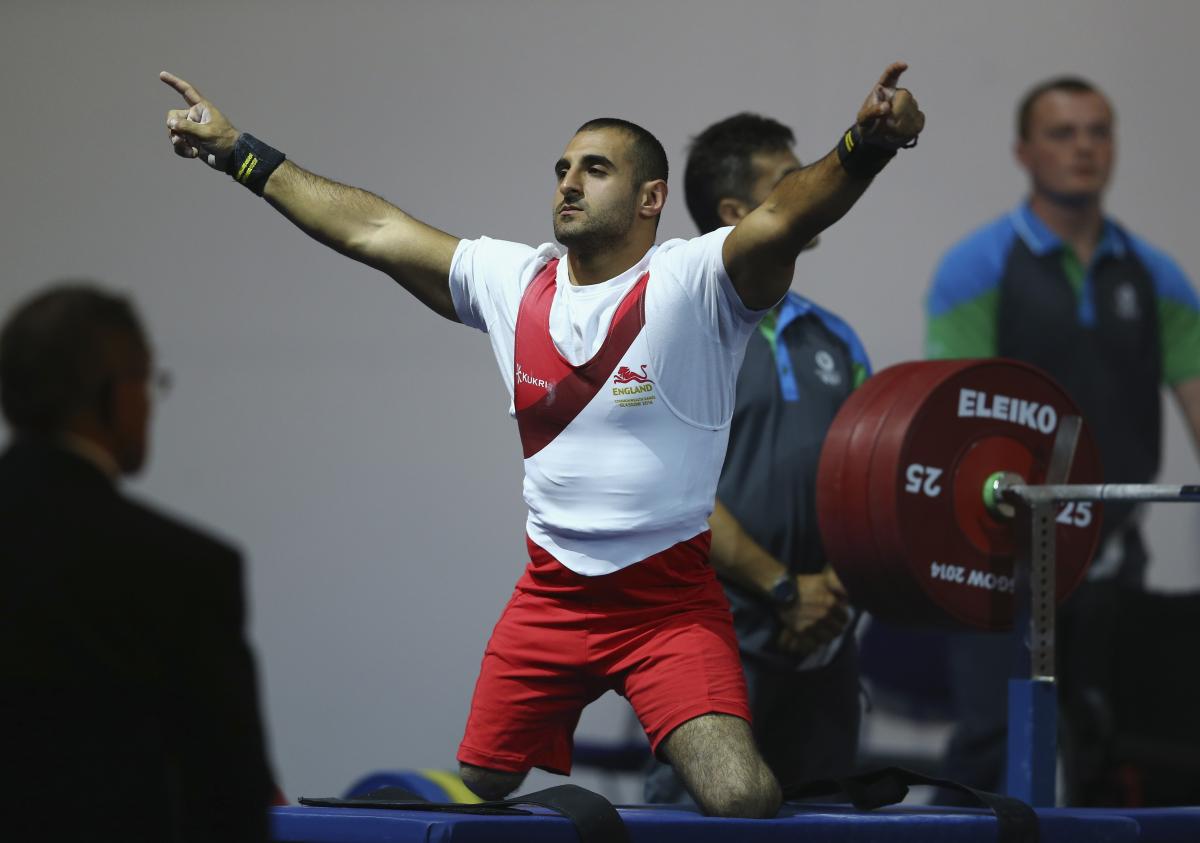 Ali Jawad - Glasgow 2014 a male powerlifter raises his arms in celebration on the bench