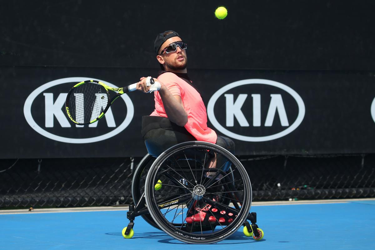 a male quad tennis player takes a shot