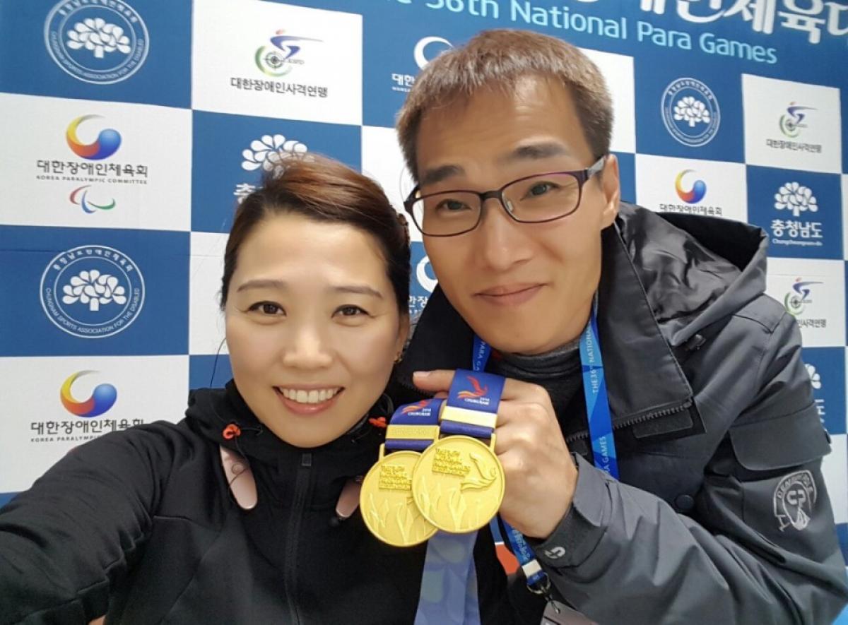 a man and a woman hold up a medal