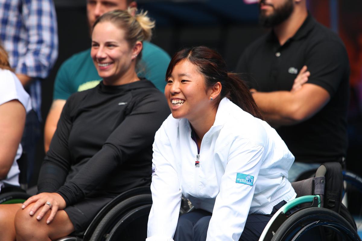 a female wheelchair tennis player smiles in delight