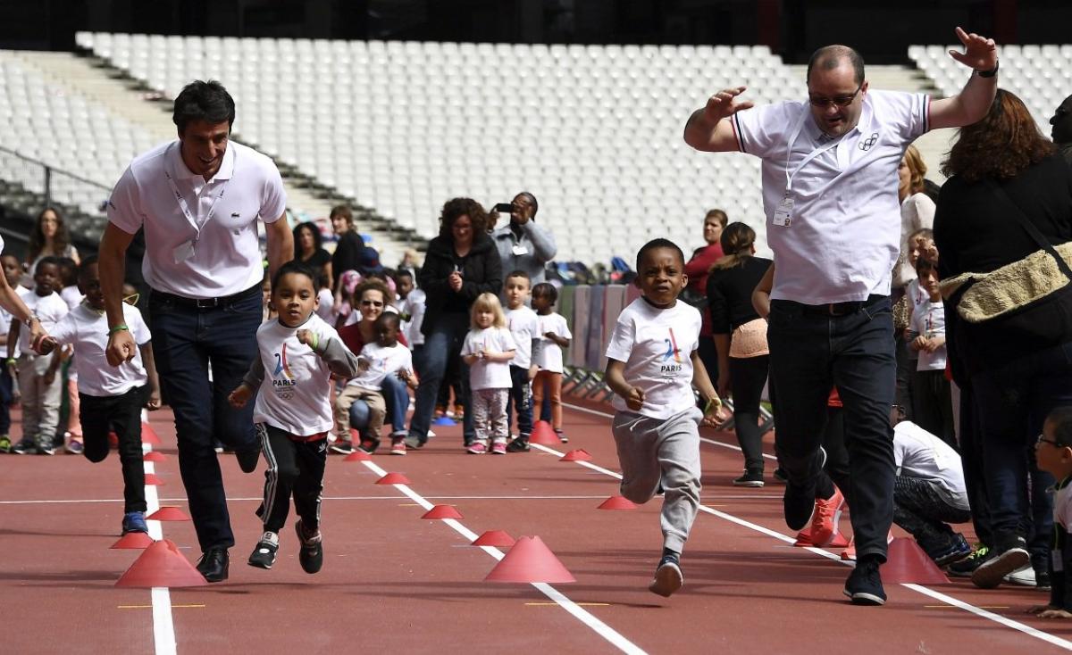 Paris 2024 Olympic and Paralympic Week Men and children running on an athletics' track