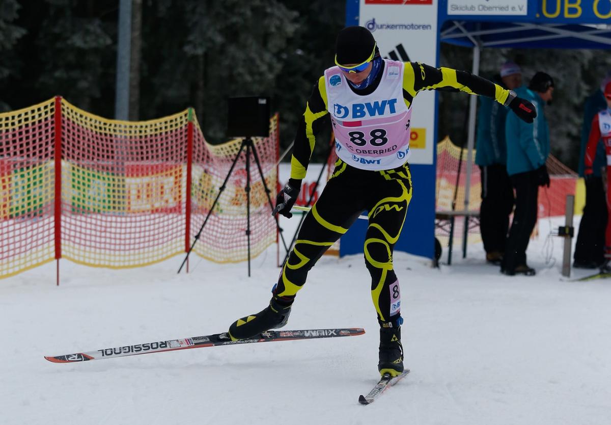 A male Para Nordic skier sprints towards the finish line