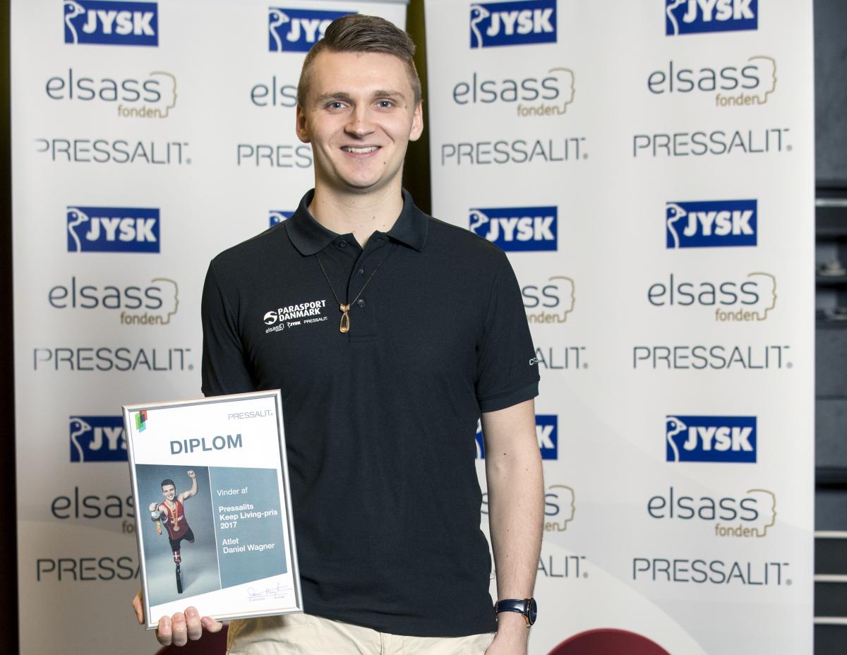 a male Para athlete holds up a certificate