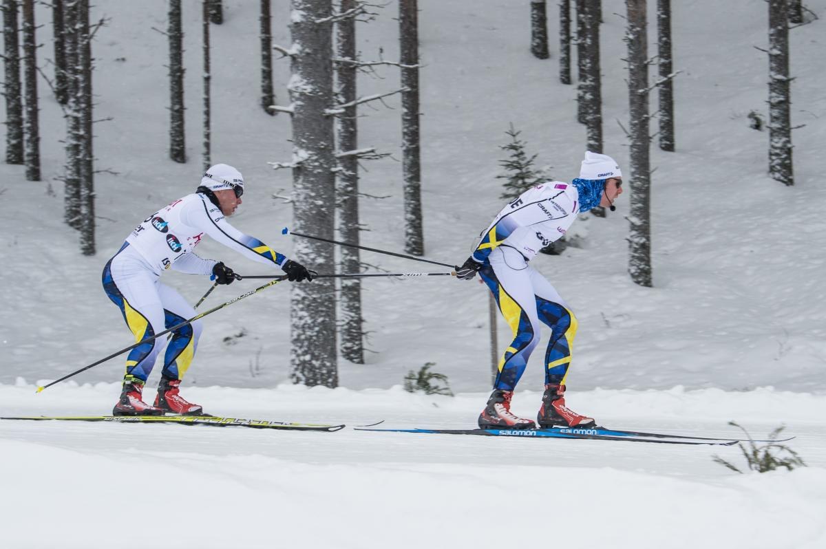 a male Nordic skier and his guide mid-race
