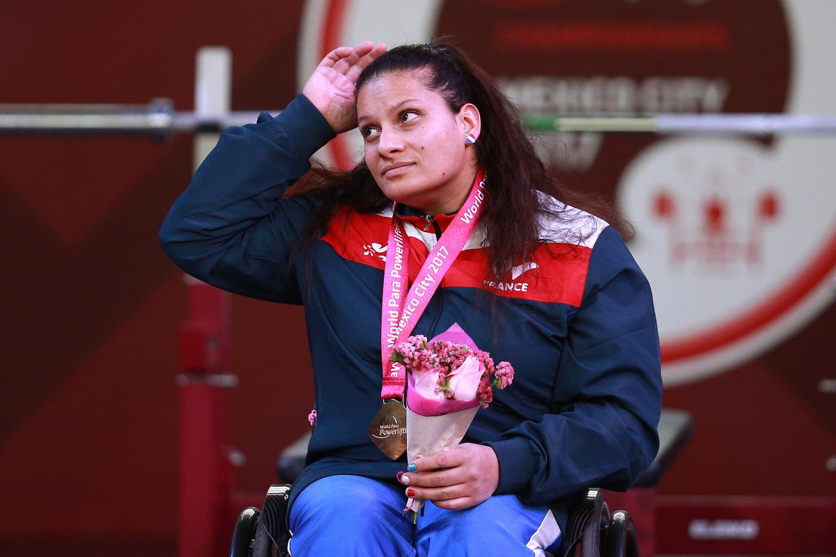 a female powerlifter on the podium with her gold medal