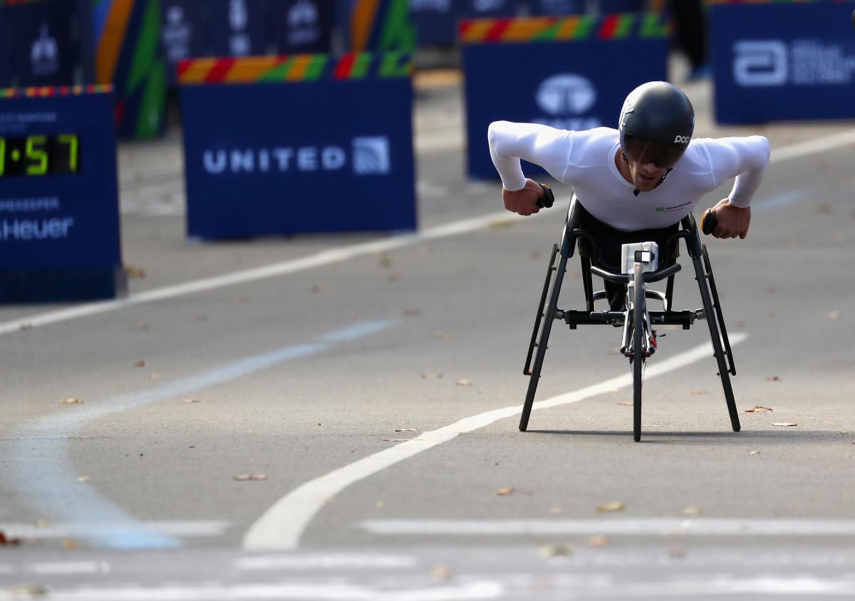 a male wheelchair racer heads towards the finish line