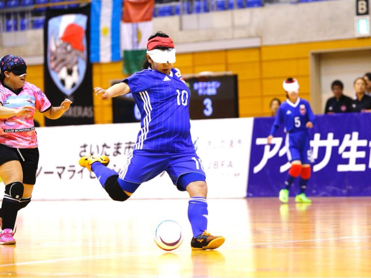 a female blind footballer takes a shot