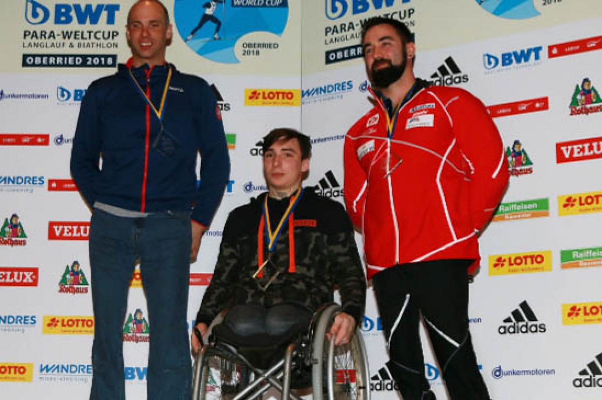 three male sit skiers on the podium