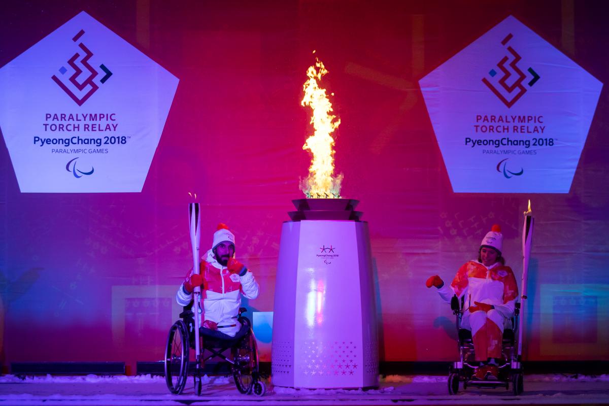 two athletes light a flame