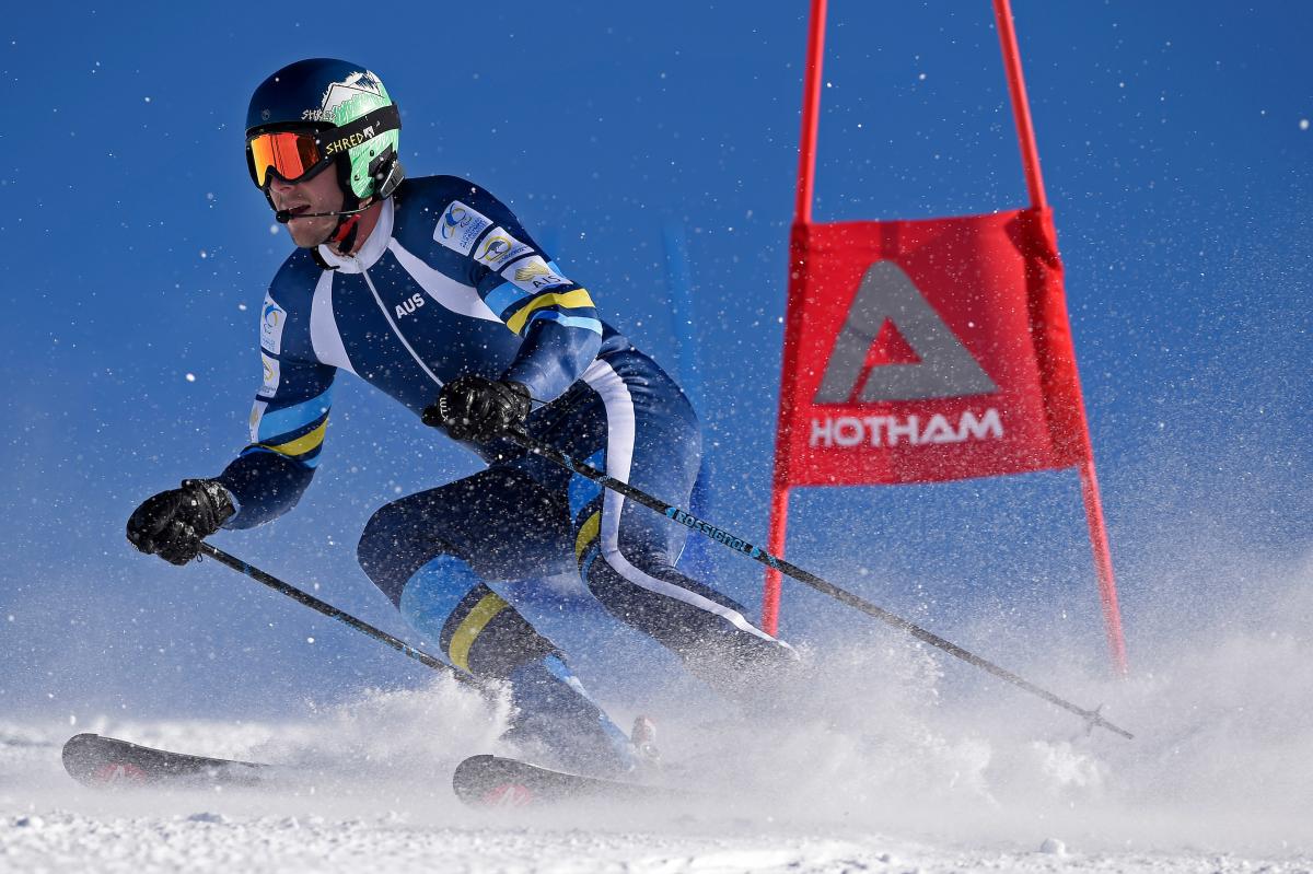 a male vision impaired skier rounds a gate