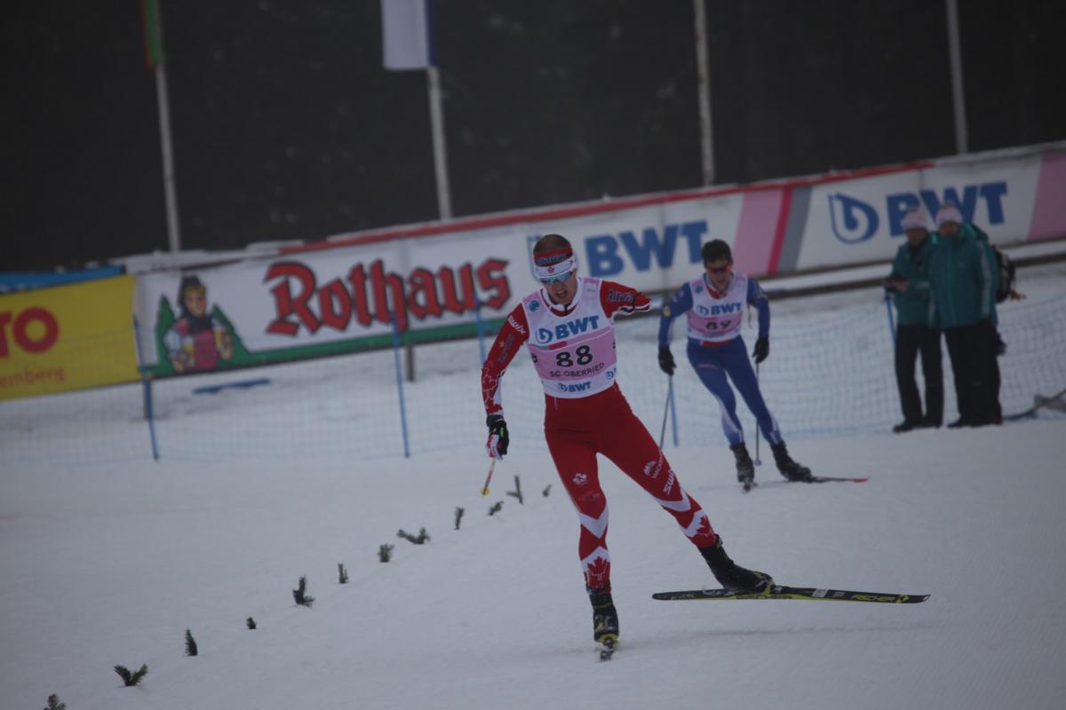 a male biathlete skies towards the finish line