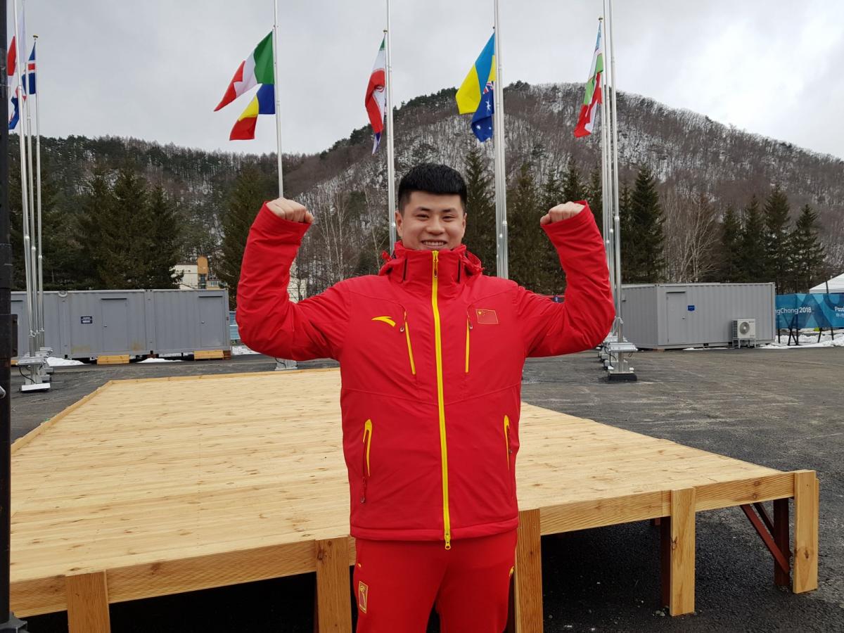 a male Para snowboarder gives a thumbs up