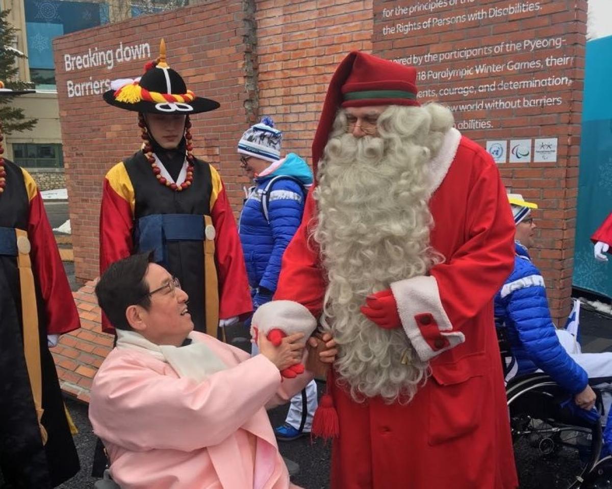 Santa Claus at the PyeongChang 2018 Paralympic Village Santa Claus shaking hands with a wheelchair athlete