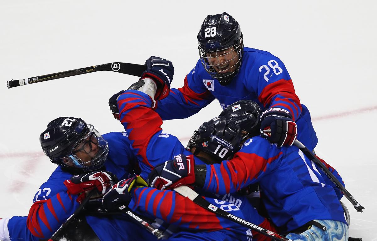 a Para ice hockey team hug in celebration