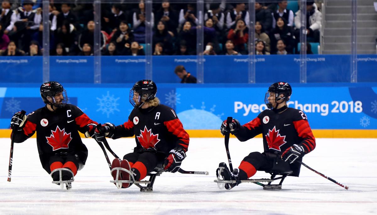 a group of Para ice hockey players celebrate on the ice