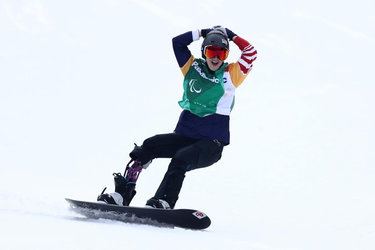 a female Para snowboarder celebrates on the snow