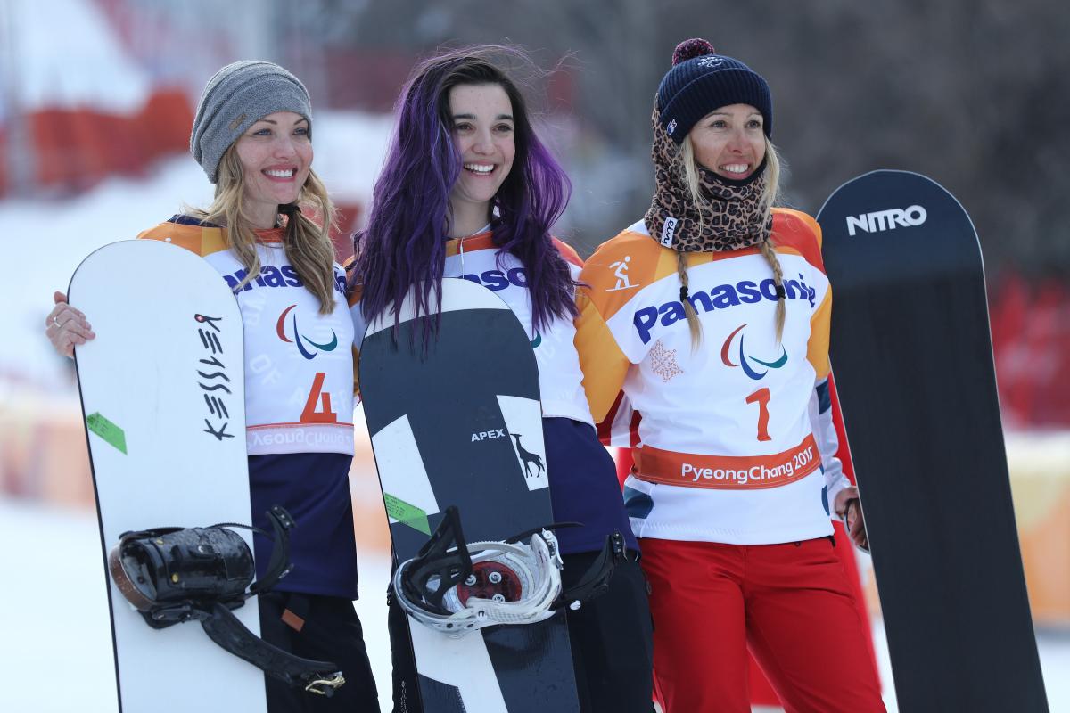 three female snowboarders on a podium