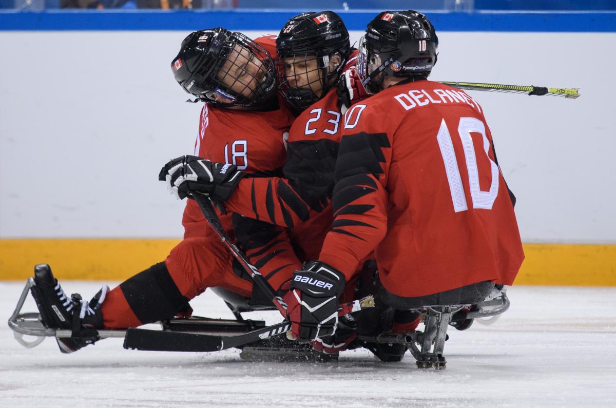 Three Para ice hockey players celebrating a goal