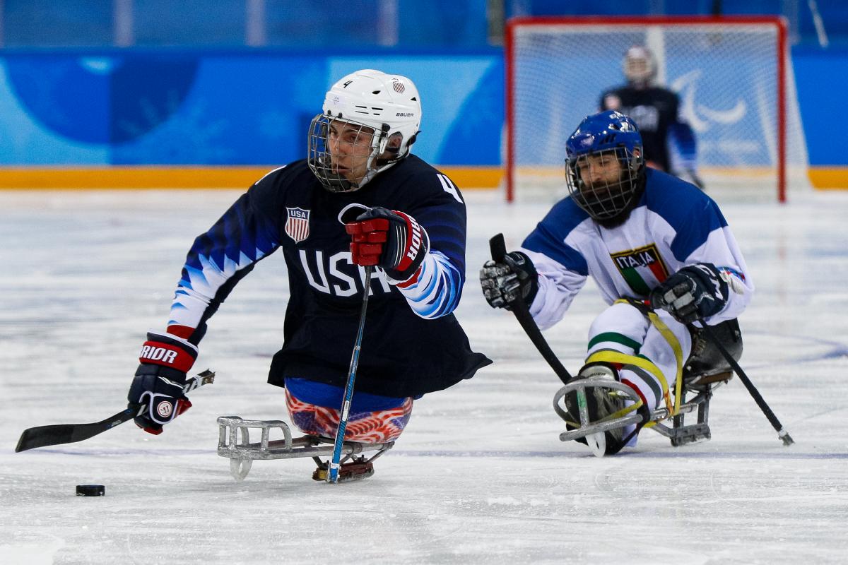 Two athletes on sledges playing Para ice hockey