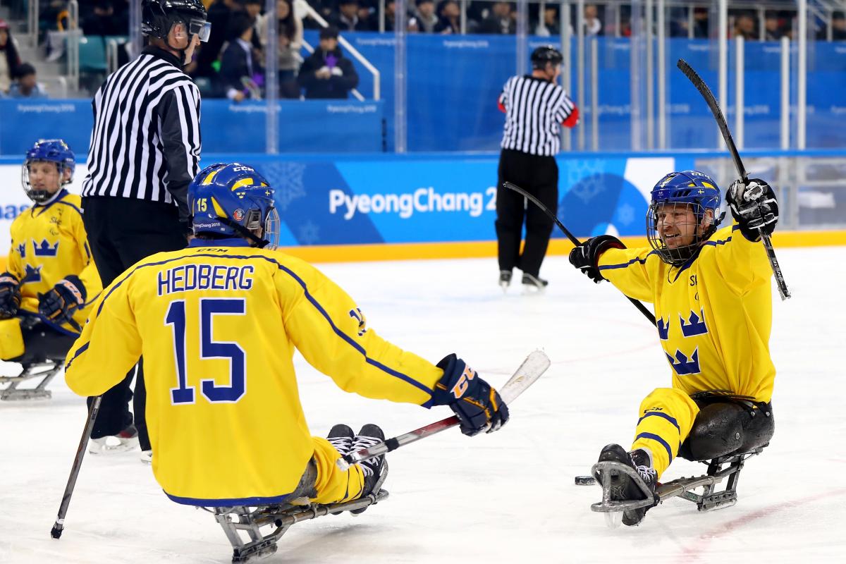 two Para ice hockey players celebrate a goal