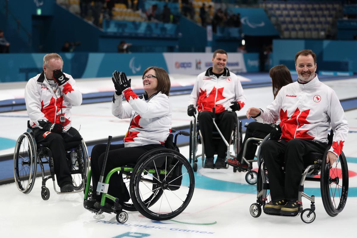 a wheelchair curling team celebrates on the ice