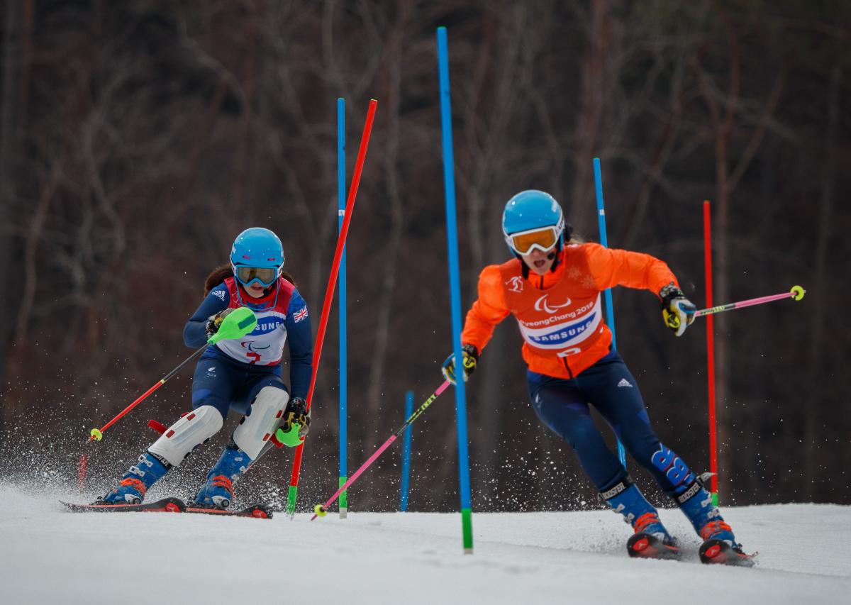 a female vision impaired skier and her guide go through the slalom gates